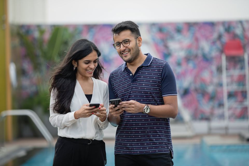 Two coworkers checking their tasks together on their phones